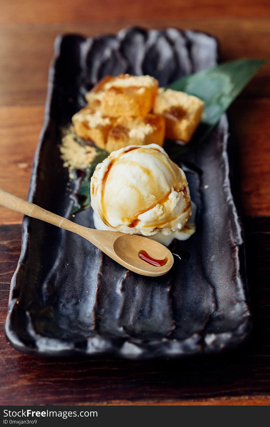 Warabi Mochi Served With A Scoop Of Vanilla Ice Cream That Topping With Caramel Served In Black Plate