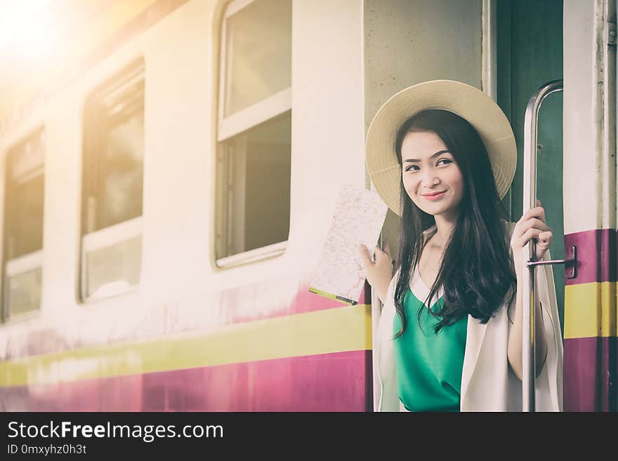 Asian woman traveler has get in the train with happiness at Hua Lamphong station at Bangkok, Thailand. beautiful brown cute door excited female girl green happy hat journey lifestyle looking map people purple railway smiling summer teen tourist transport transportation trip vacation white window yellow young