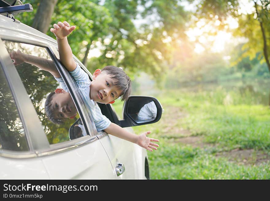 Happy boy looks out from auto window and greets somebody, Happy kids travel by the car.