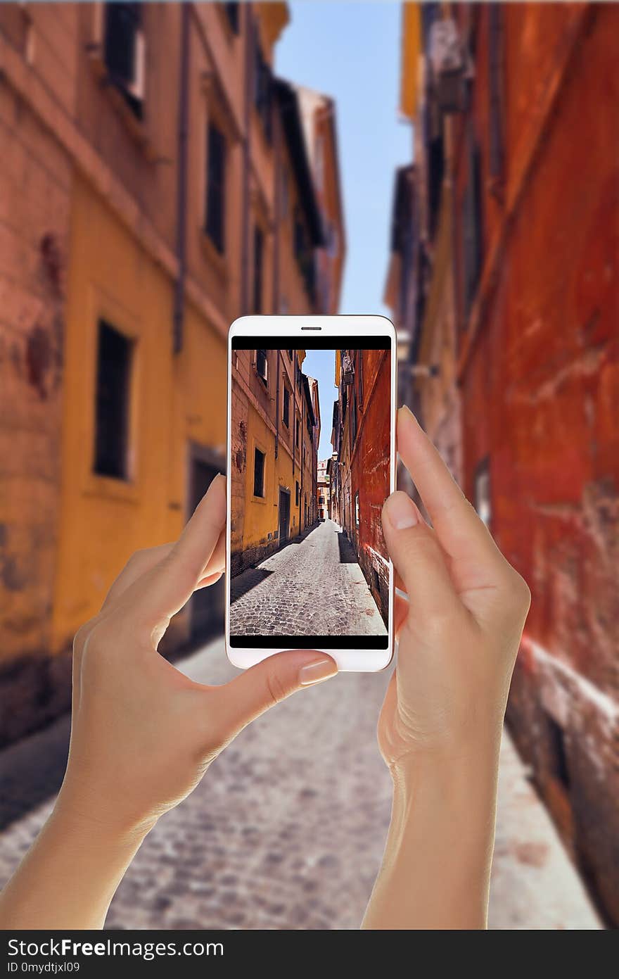 A tourist is taking a photo of narrow Italian street with colorful houses without people on a sunny day Rome, Italy on a mobile phone. A tourist is taking a photo of narrow Italian street with colorful houses without people on a sunny day Rome, Italy on a mobile phone