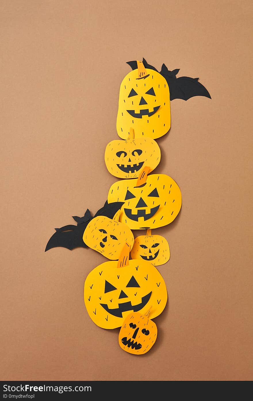 Different handcraft scary pumpkins and bats on a brown background with space for text. Creative composition for