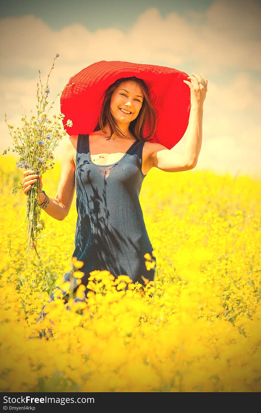 Beautiful woman with a bouquet in a red hat on a sunny day amidst wildflowers. portrait, close-up. style and fashion. retro and vintage. image filter retro style