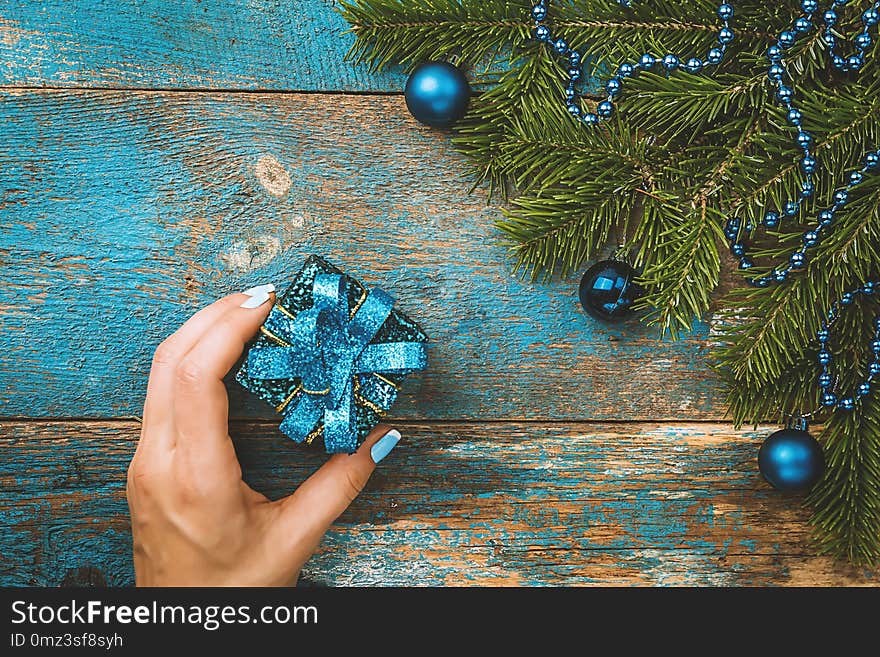 Woman`s hands holding christmas or new year decorated gift box over christmas decorated background, top view. Woman`s hands holding christmas or new year decorated gift box over christmas decorated background, top view