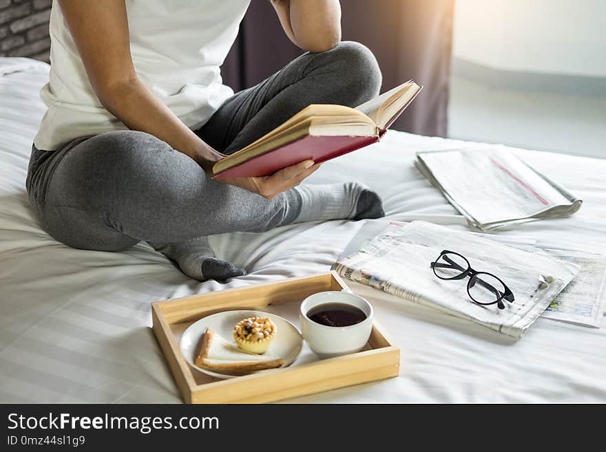 Woman reading book or newspaper and drinking coffee breakfast on