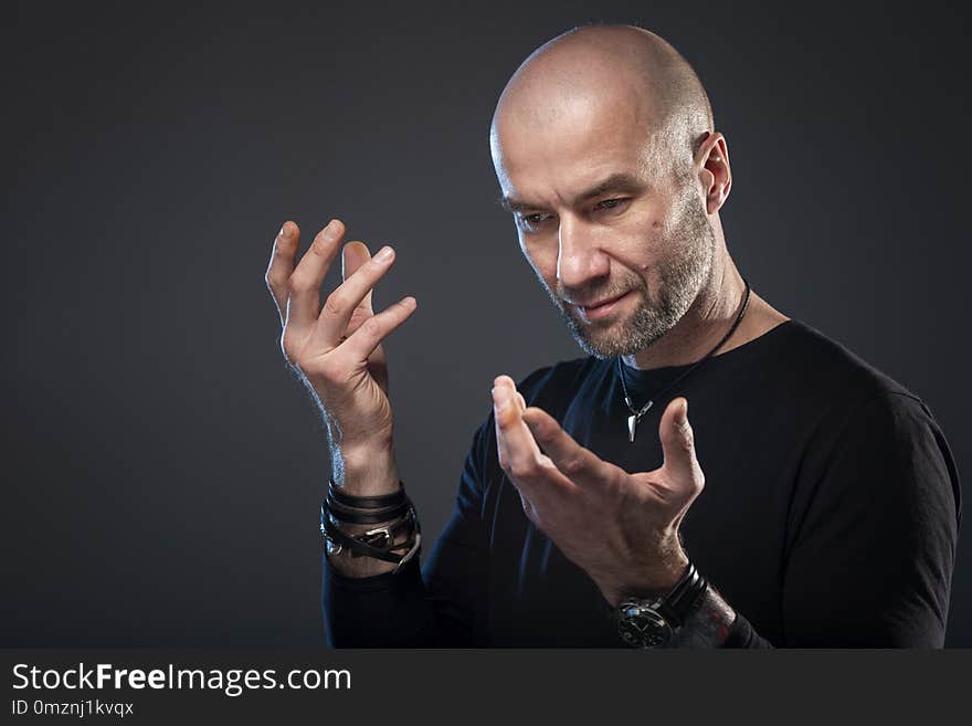 Brutal bald man, dark background, close-up