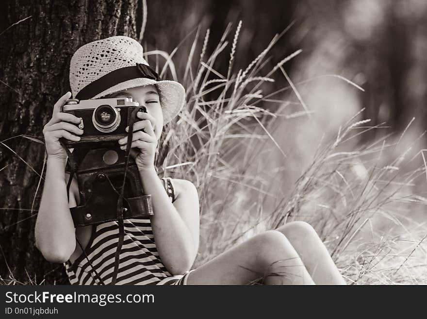 Photo of the beautiful girl taking photos with her camera near the tree . Image in black and white color style. Photo of the beautiful girl taking photos with her camera near the tree . Image in black and white color style