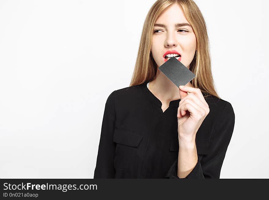 Cheeky girl in black dress and with red lips, holds credit card, white background, black Friday