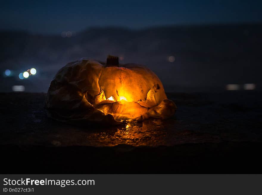 Horror Halloween concept. Close up view of scary dead Halloween pumpkin glowing at dark background.