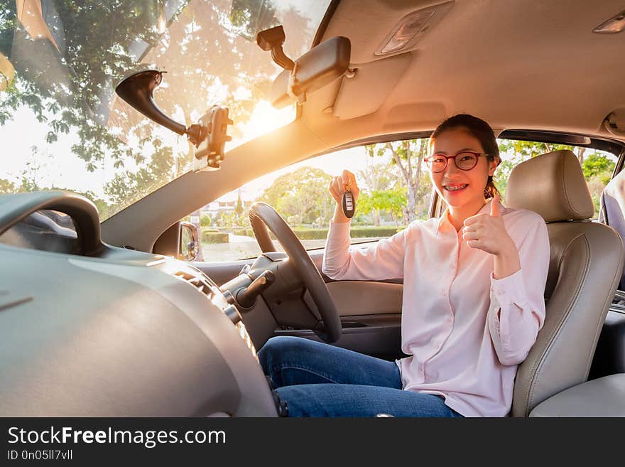 Young woman holding a key of her new car, sale car concept