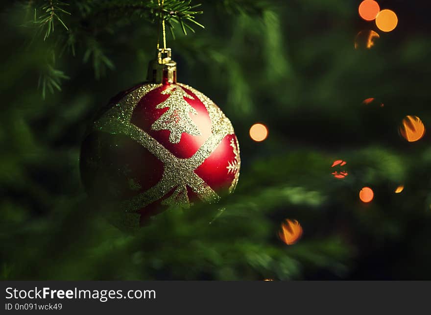 Red Golden Christmas ball on the background of fir branches and lights of garlands, New Yaer card, selective focus. Red Golden Christmas ball on the background of fir branches and lights of garlands, New Yaer card, selective focus