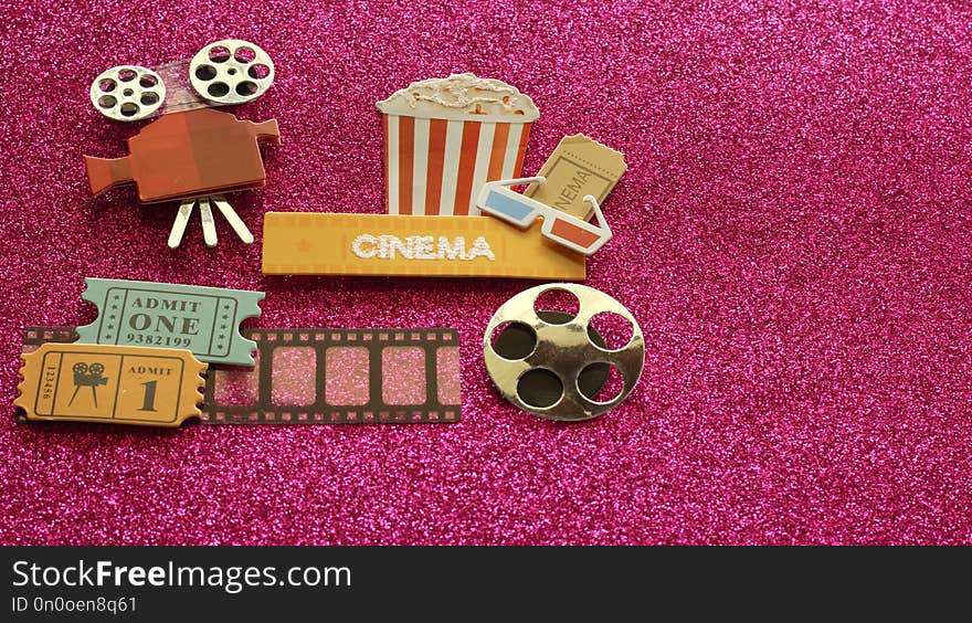 A Tub of popcorn with a cinema sign with 3d glasses and movie tickets on a film strip with a projector on a dark pink sparkling background with writing space. A Tub of popcorn with a cinema sign with 3d glasses and movie tickets on a film strip with a projector on a dark pink sparkling background with writing space.