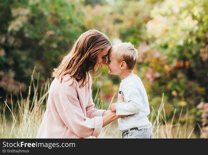 Mom and son hug and laugh in the autumn park. Space for text.