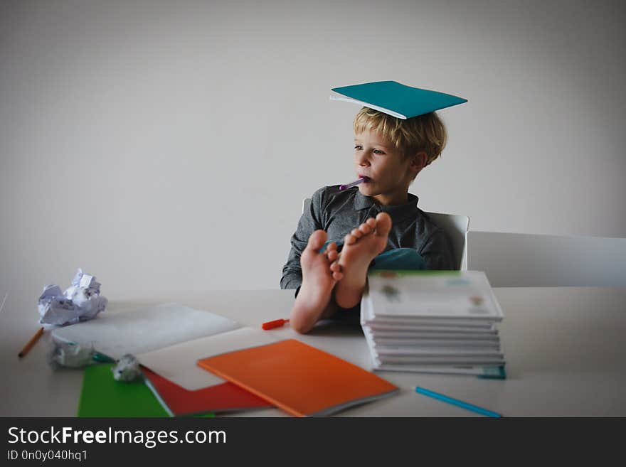 Young boy pretend doing homework relaxed at home, difficult learning