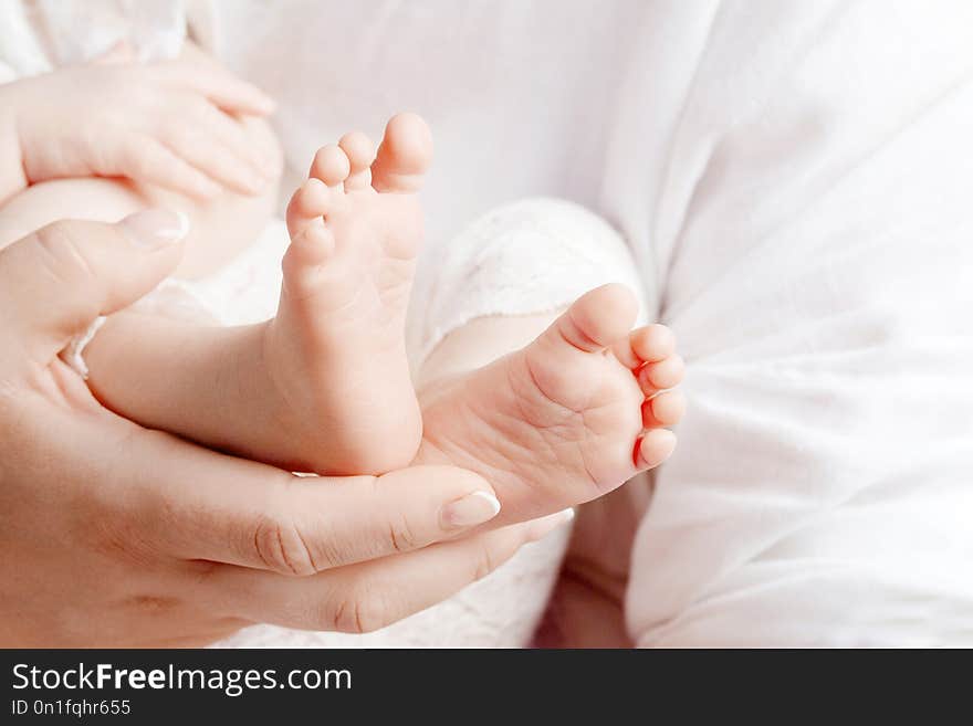 Baby feet in mother hands. Tiny newborn baby`s feet on female hands closeup. Mom and her child. Happy Family concept. Beautiful conceptual image of parenthood