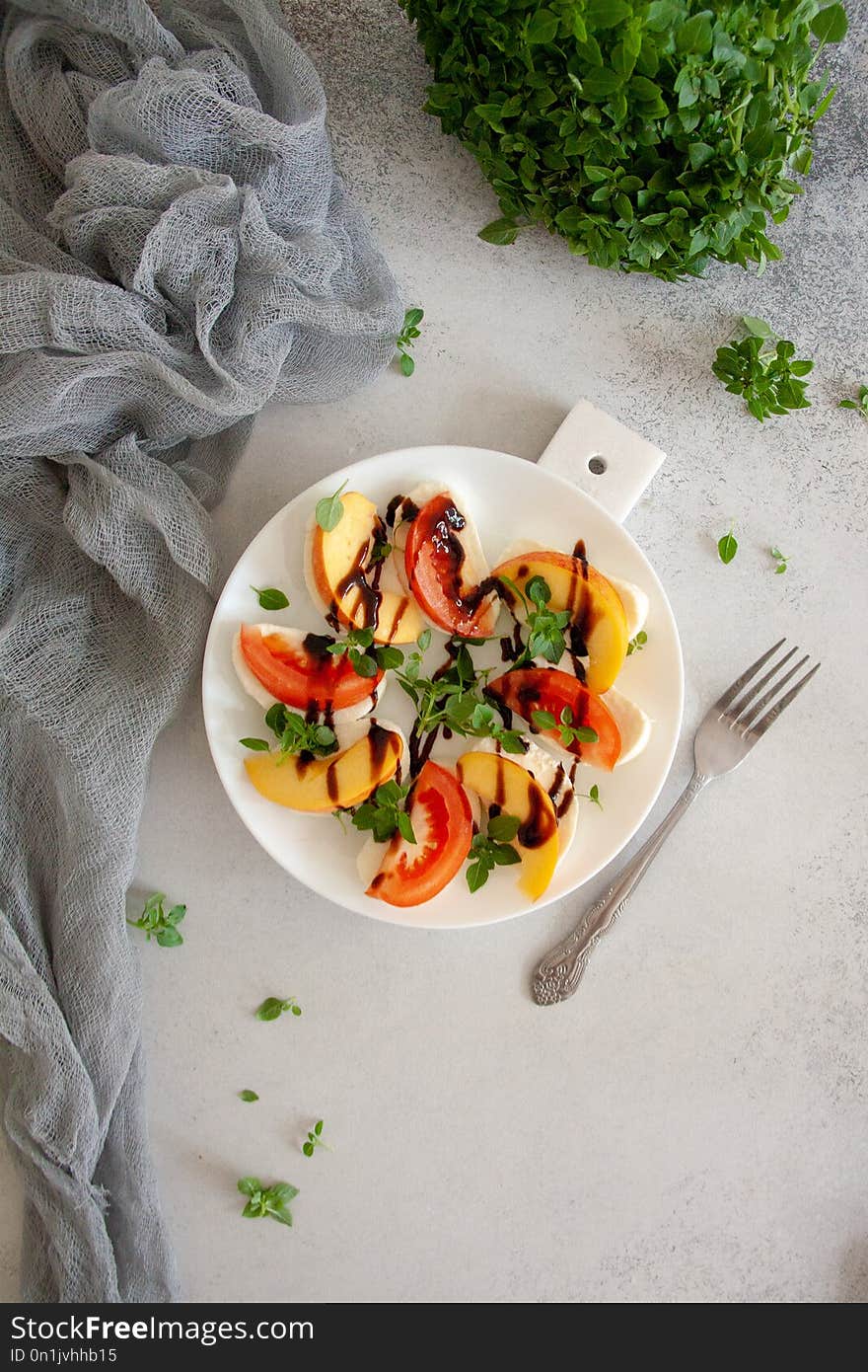 Italian fresh salad with mozzarella, tomato, peach and basil on a white plate. Italian fresh salad with mozzarella, tomato, peach and basil on a white plate