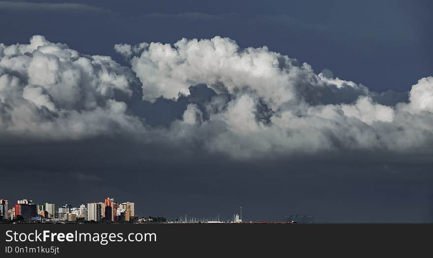 Long shot of skyscrappers near sea with stormy clouds over them