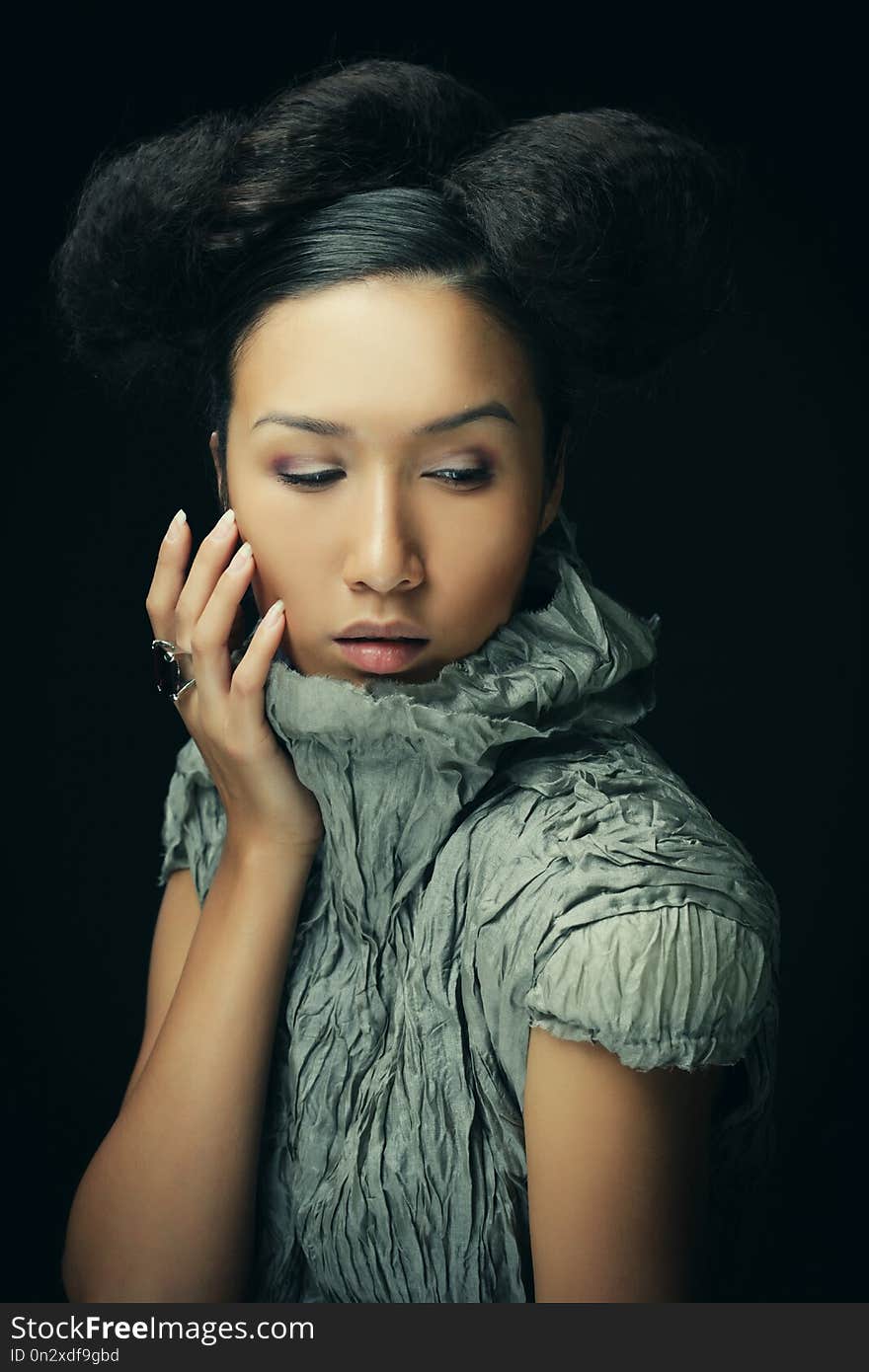 Beauty and fashion concept: young Asian fashion model in grey dress against black background