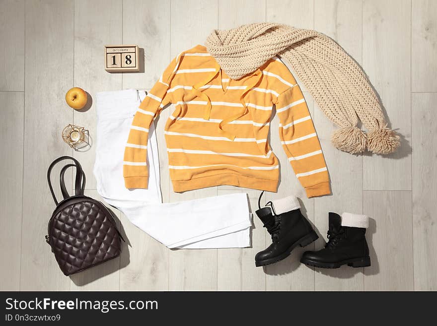 Set of stylish winter outfit on wooden background, flat lay