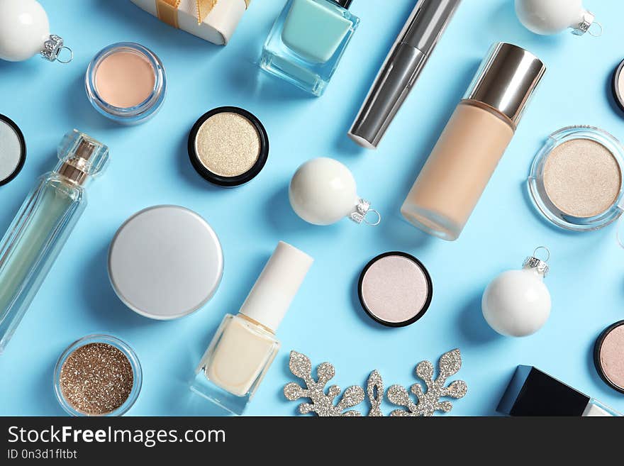 Flat lay composition with makeup products and Christmas decor on color background