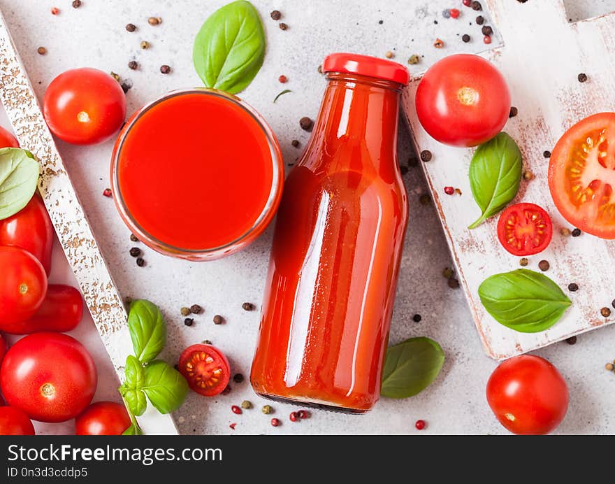 Bottle of fresh organic tomato juice with fresh raw tomatoes basil and pepper in box on stone kitchen background