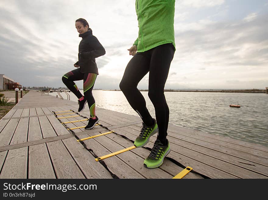 Group of young people training outdoors,couple of athletes do runners exercises, sea or river background. Group of young people training outdoors,couple of athletes do runners exercises, sea or river background