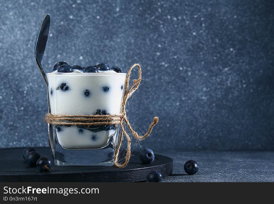 Yogurt with blue blackthorn berries in a glass. Berry dessert.