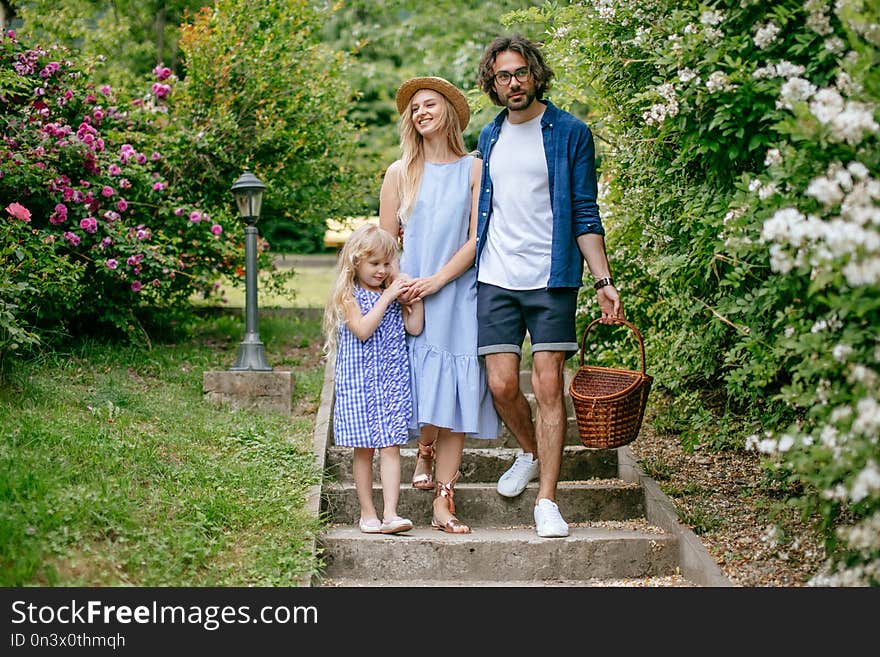 Happy father mother and daughter in park. family outdoor lifestyle. Happy family walking together on stairs, having fun outdoor after picnic. Happy father mother and daughter in park. family outdoor lifestyle. Happy family walking together on stairs, having fun outdoor after picnic