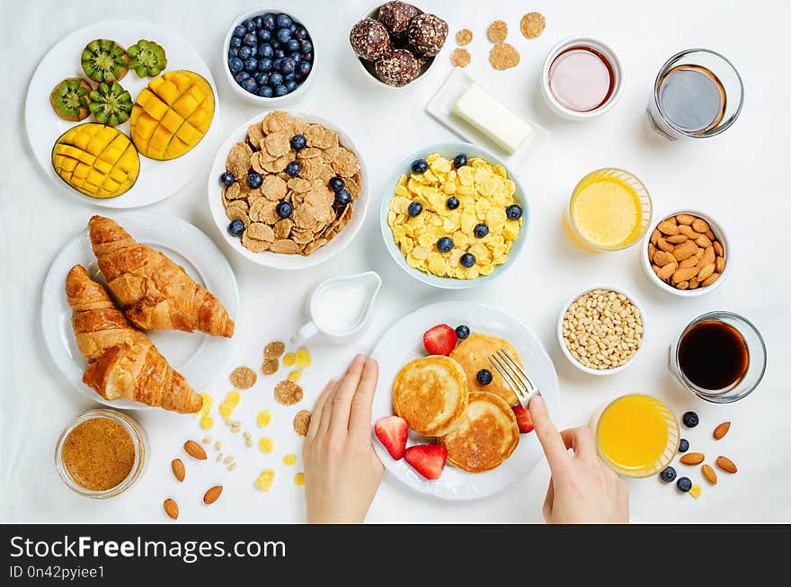 Breakfast table setting with flakes, juice, croissants, pancakes and fresh berries. toning. selective focus