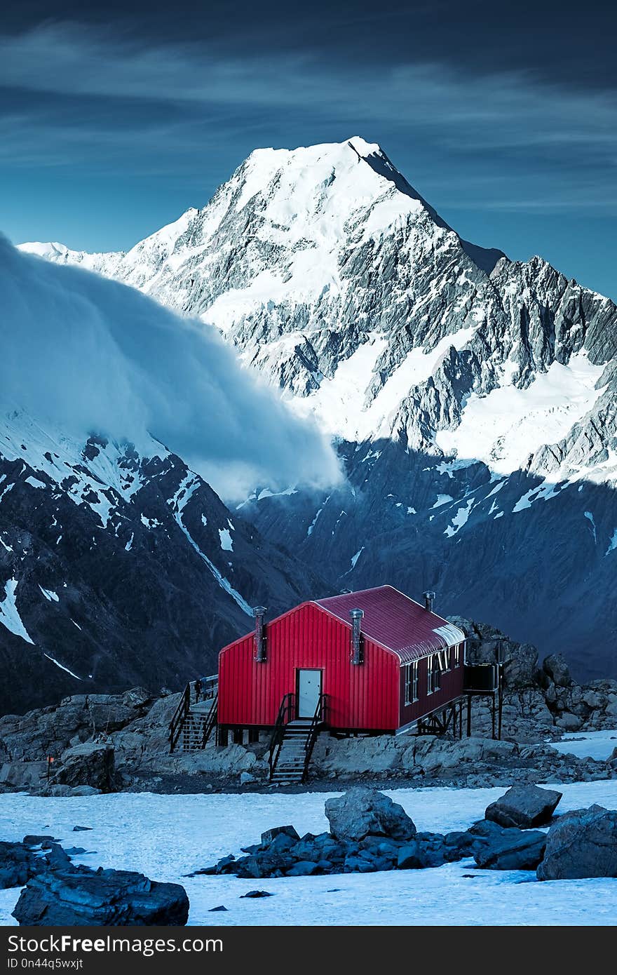 Winter landscape view of red mountain hut and Mt Cook peak in the background, New Zealand. Winter landscape view of red mountain hut and Mt Cook peak in the background, New Zealand