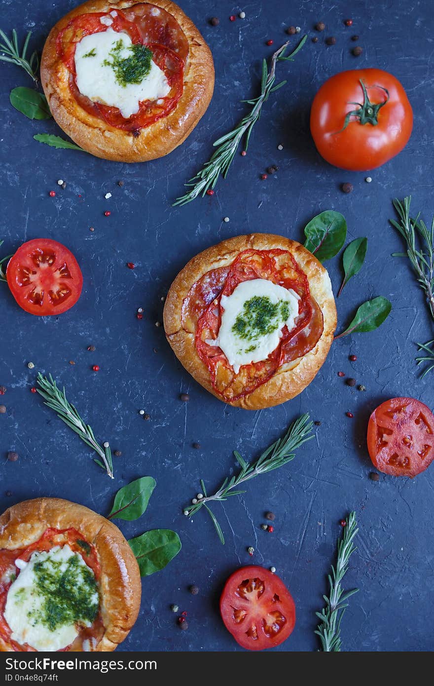 Three Homemade Mini Pizza with Tomatoes, Cheese and Bacon, Injuries and Spices on Dark Background Vertical