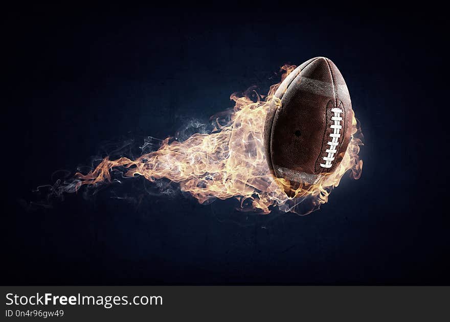 Rugby ball in a fire flames on dark background. Mixed media. Rugby ball in a fire flames on dark background. Mixed media