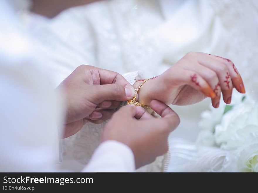 Groom put a jewelry to bride`s hand.