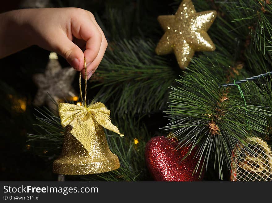 Close-up of Child’s Hand Putting a Christmas Ornament on the Tree. Close-up of Child’s Hand Putting a Christmas Ornament on the Tree