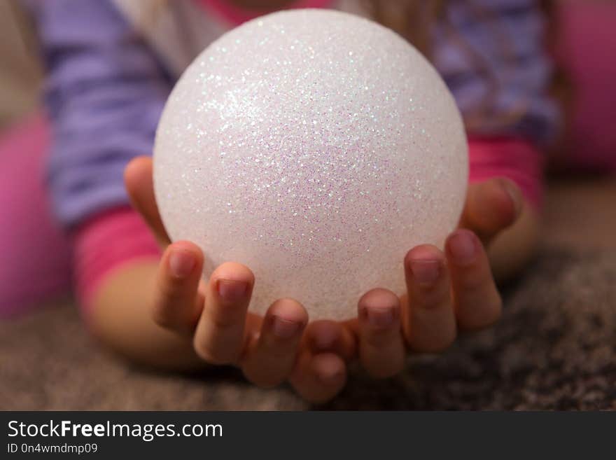 Closeup Of Child’s Hands Holding White Glitter Ball. Closeup Of Child’s Hands Holding White Glitter Ball