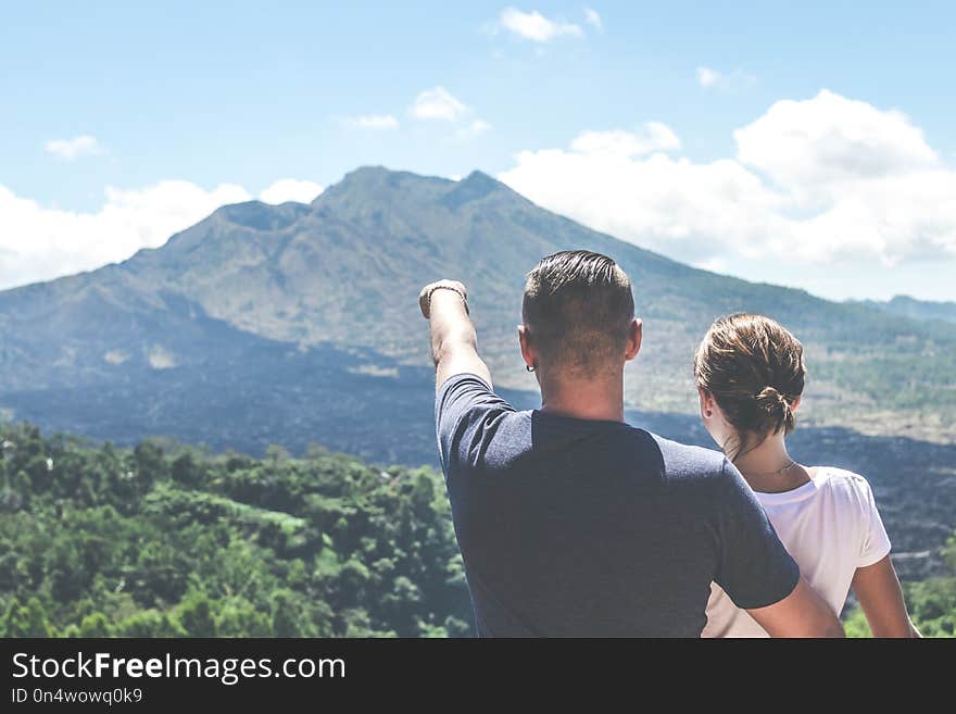 Young couple standing on a mountain background. Volcano Batur, Bali island.