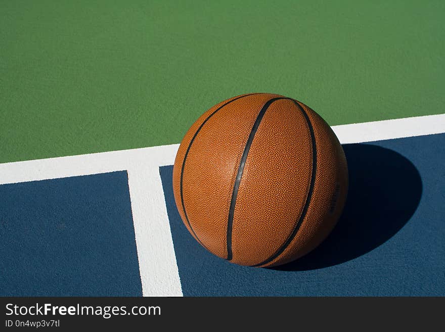 Leather basketball on colorful outdoor court - great background for your hoops related event. Leather basketball on colorful outdoor court - great background for your hoops related event
