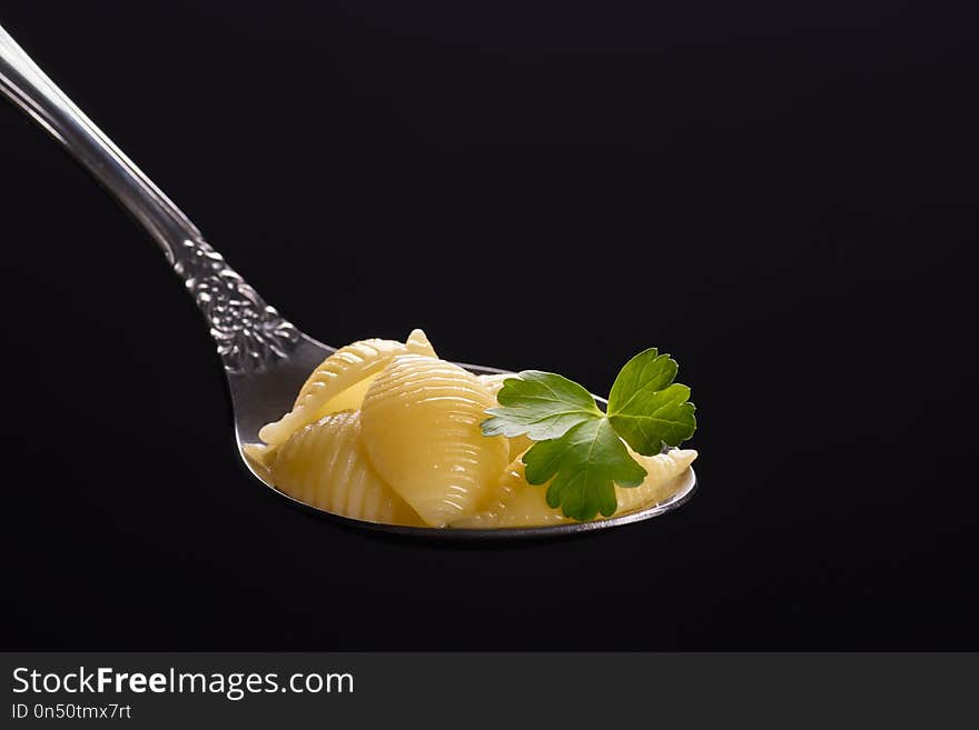 Pasta in a spoon with parsley leaves. large on black background. Pasta in a spoon with parsley leaves. large on black background.