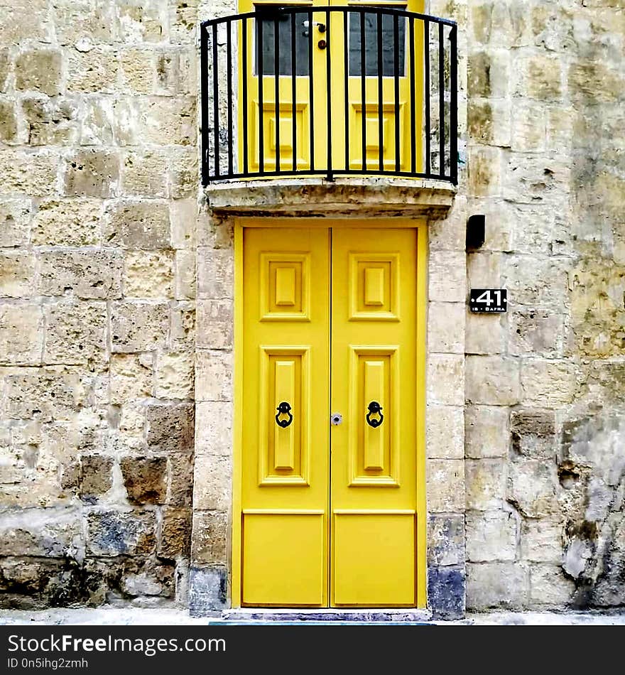 Old wooden doors painted yellow with antique cast iron handles. Entrance doors to the apartment in Malta. Old wooden doors painted yellow with antique cast iron handles. Entrance doors to the apartment in Malta