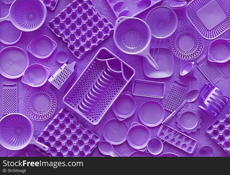 Close up flat lay of different purple violet color painted kitchen utensils and tools, grater, spoon, egg carton, plastic disposable plates, elevated top view, directly above. Close up flat lay of different purple violet color painted kitchen utensils and tools, grater, spoon, egg carton, plastic disposable plates, elevated top view, directly above