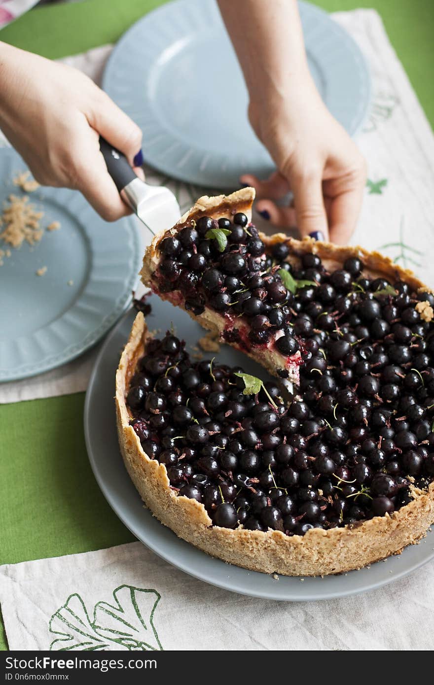 Berry sand pie: the girl slicing the cake and spreads the pieces on the blue plates.