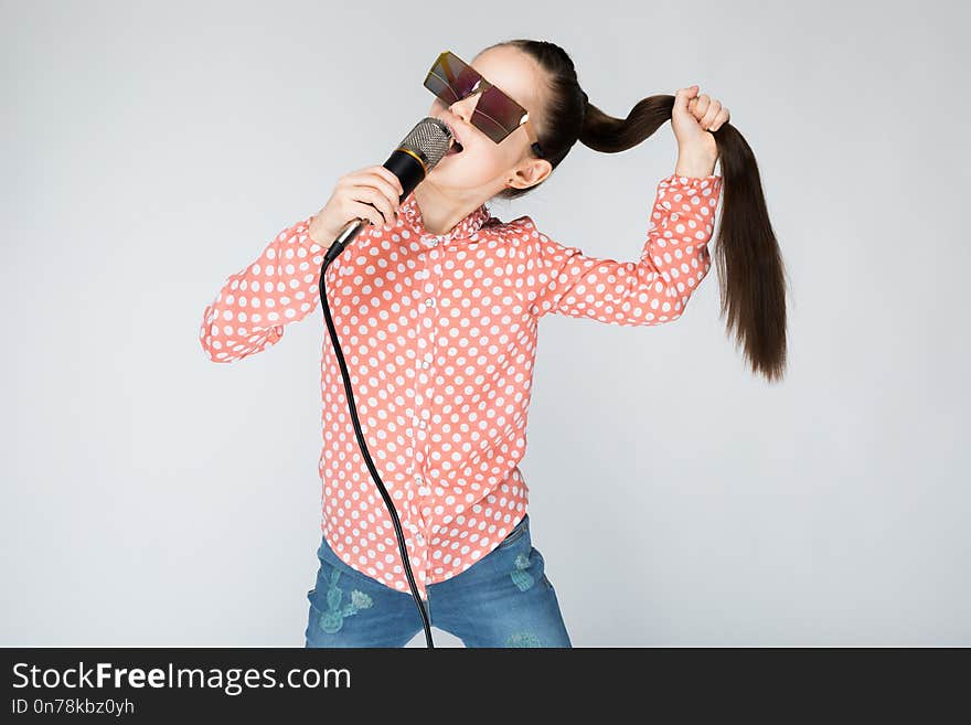 Girl On A Gray Background Singing Into The Microphone.