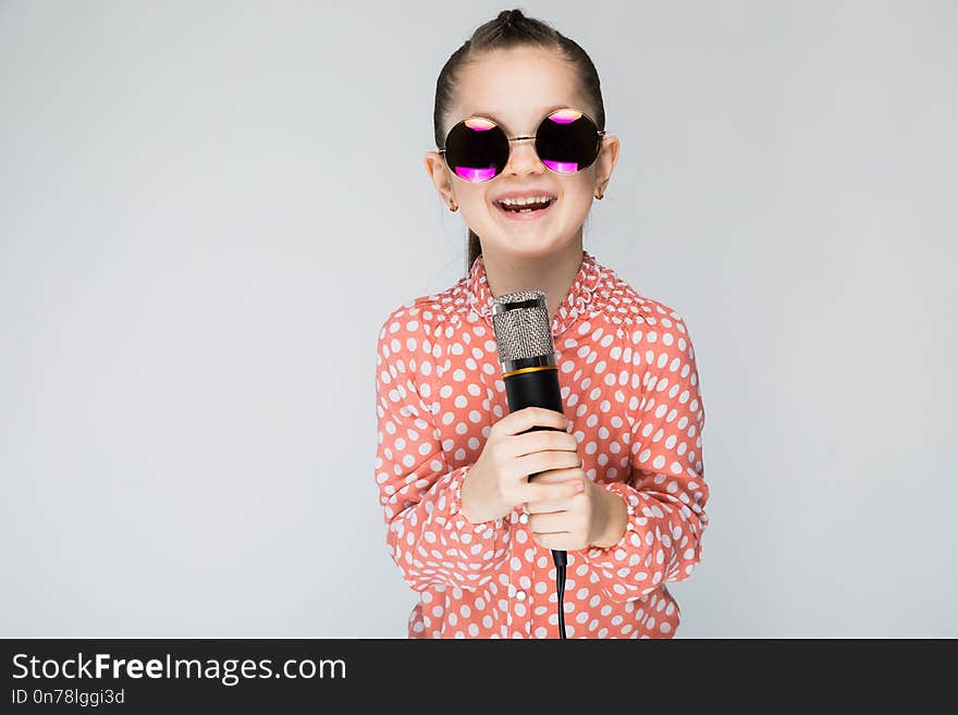 Girl on a gray background singing into the microphone.