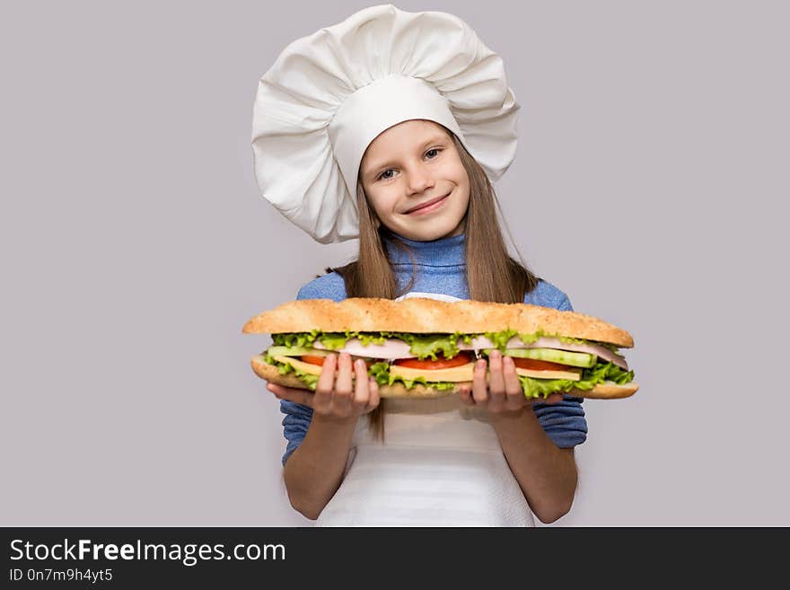 Happy little girl with hot dog and chef uniform isolated on white background. Kid chef.