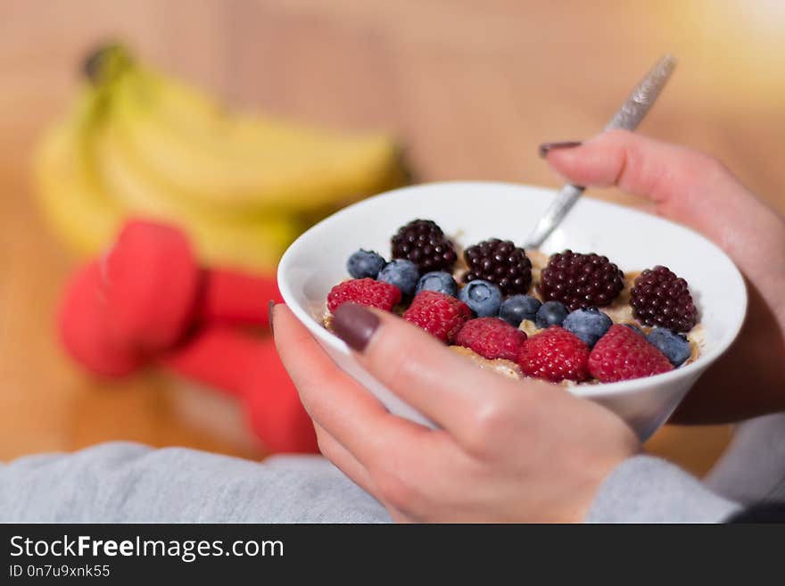 Woman Eating Oats Porridge In Bowl Decorated With Blackberries, Raspberries And Blueberries