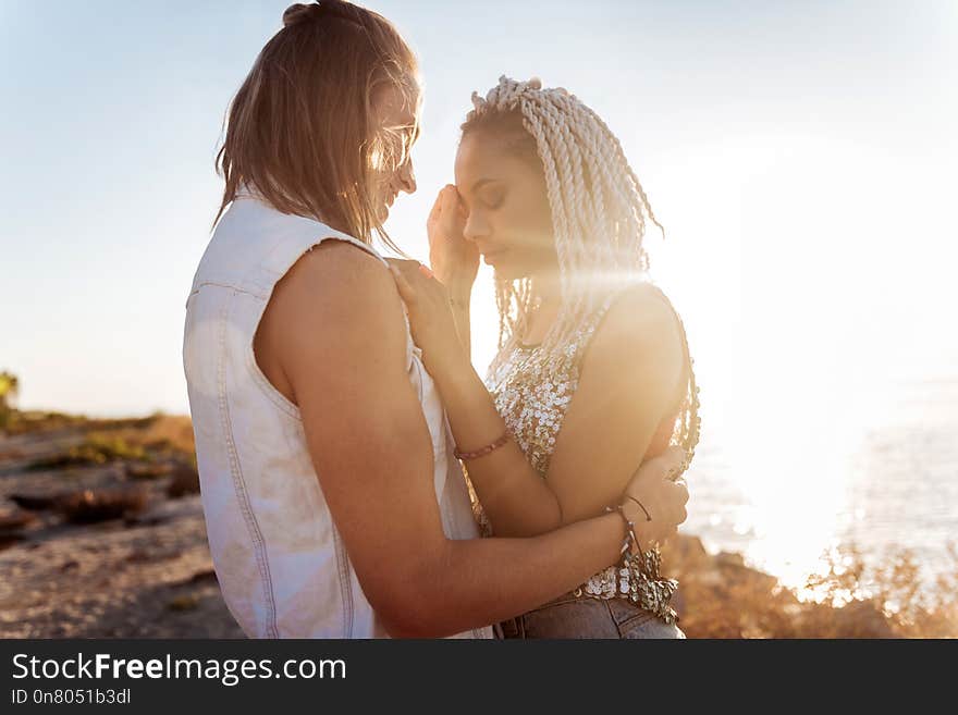 Hugging man. Stylish young women with dreadlocks feeling happy hugging her strong handsome man. Hugging man. Stylish young women with dreadlocks feeling happy hugging her strong handsome man