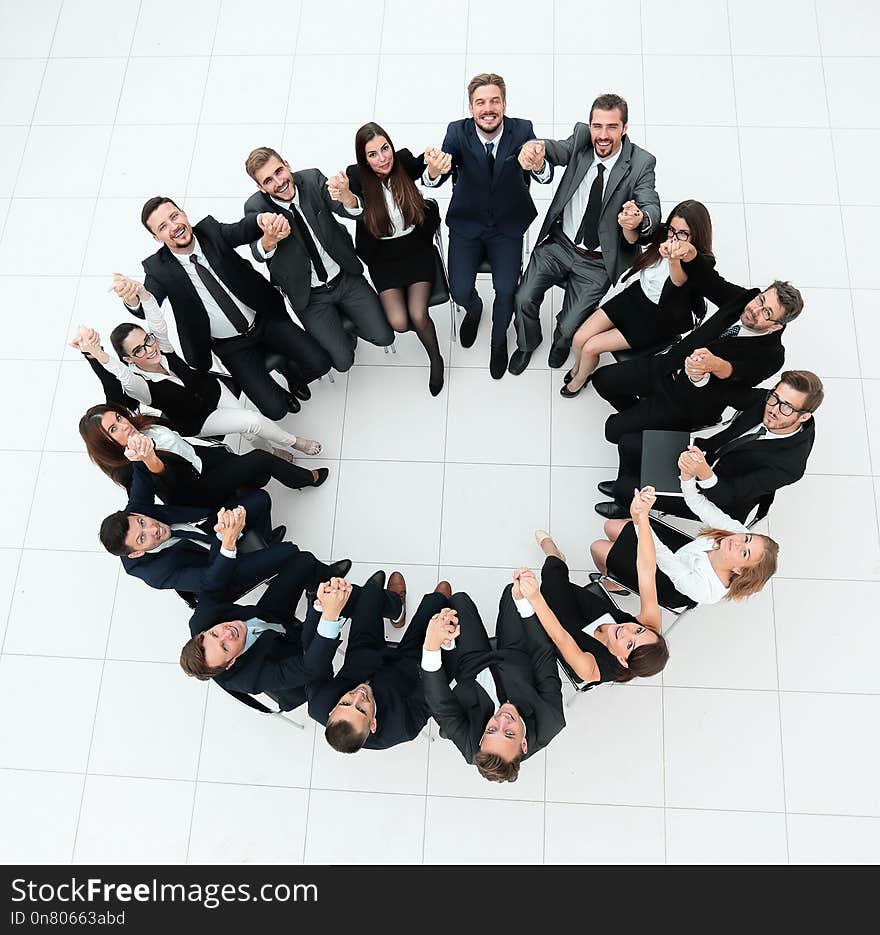 Large business team sitting in a circle and holding each other`s hands.the view from the top. Large business team sitting in a circle and holding each other`s hands.the view from the top.