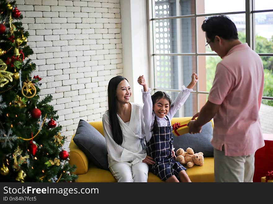 Family decorating a Christmas tree and Father giving Christmas Gift,Christmastime celebration and Happy new year.