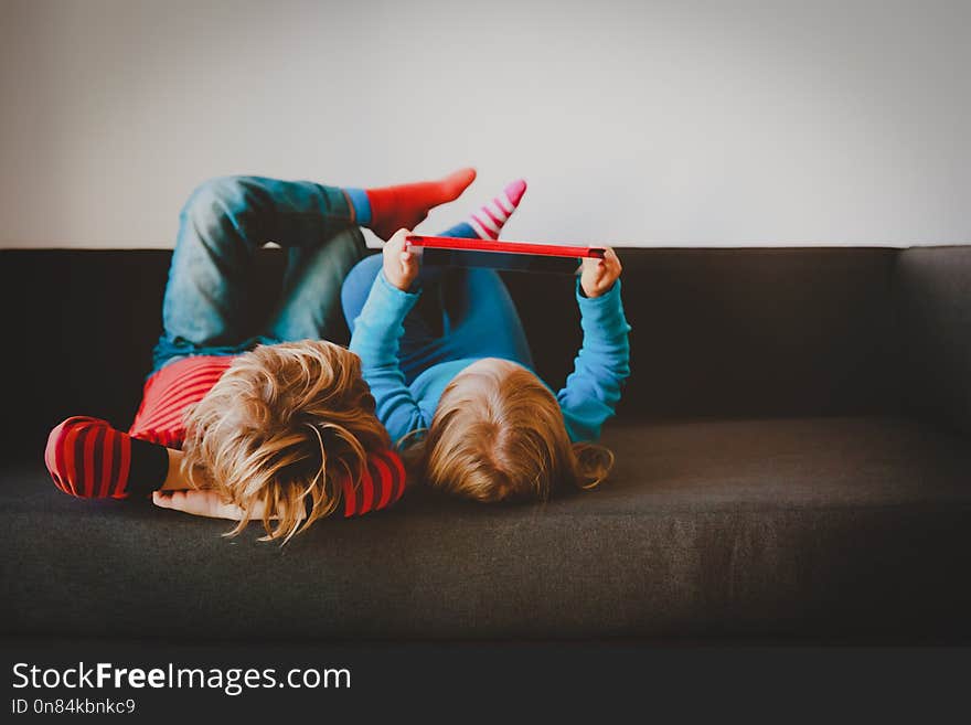 Little boy and girl looking at touch pad at home