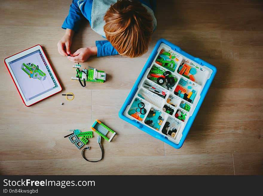 Little boy building robot from plastic blocks and programming it with touch pad. Little boy building robot from plastic blocks and programming it with touch pad