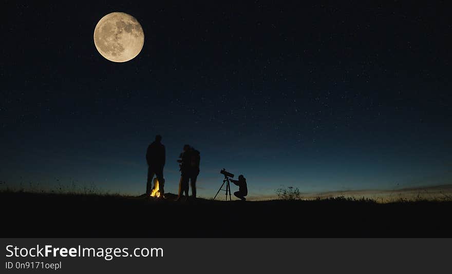 Silhouettes of people gathering together in nature looking on big moon with burning campfire near in night. Silhouettes of people gathering together in nature looking on big moon with burning campfire near in night